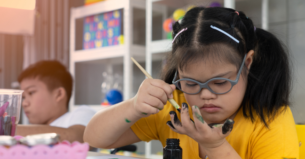 young girl with glasses painting her fingers