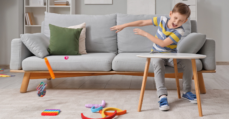 young boy angrily swiping his toys off a table