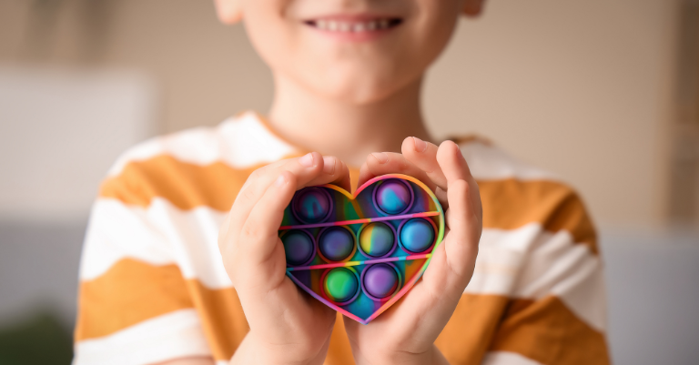 Child holding a colorful heart-shaped toy, representing support for children navigating autism diagnostic criteria.