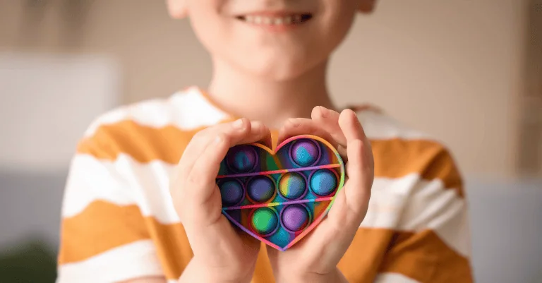 Child holding a colorful heart-shaped toy, representing support for children navigating autism diagnostic criteria.
